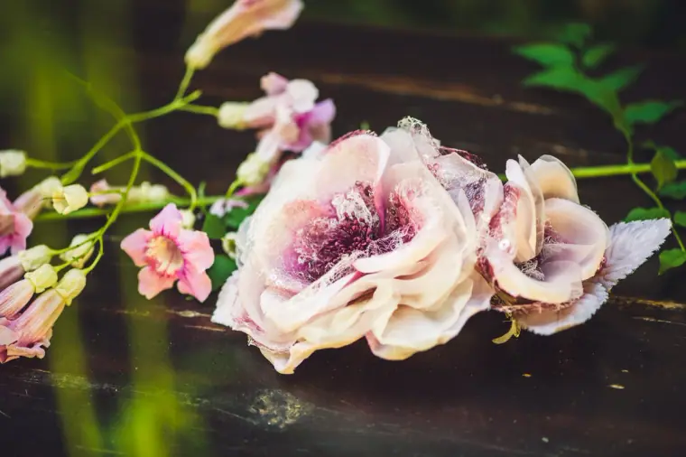 Pink fabric bridal flowers laid among delicate blossom on a dark table