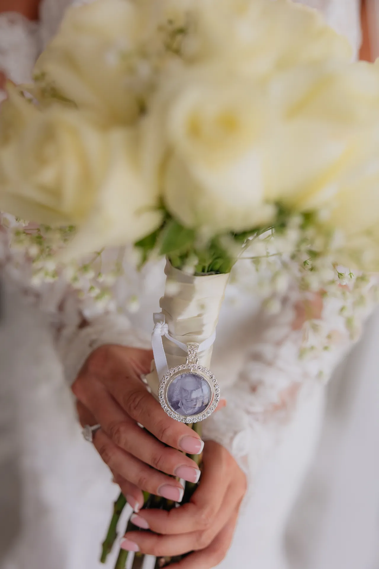 Close-up of a white rose bouquet with a photo charm wrapped around the stems