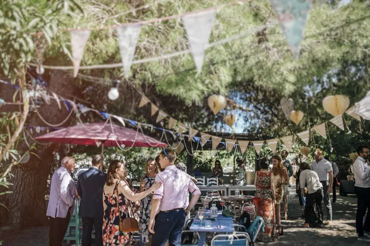 Guests gathering beneath bunting and paper lanterns in the garden at Hidden Bar, Ibiza