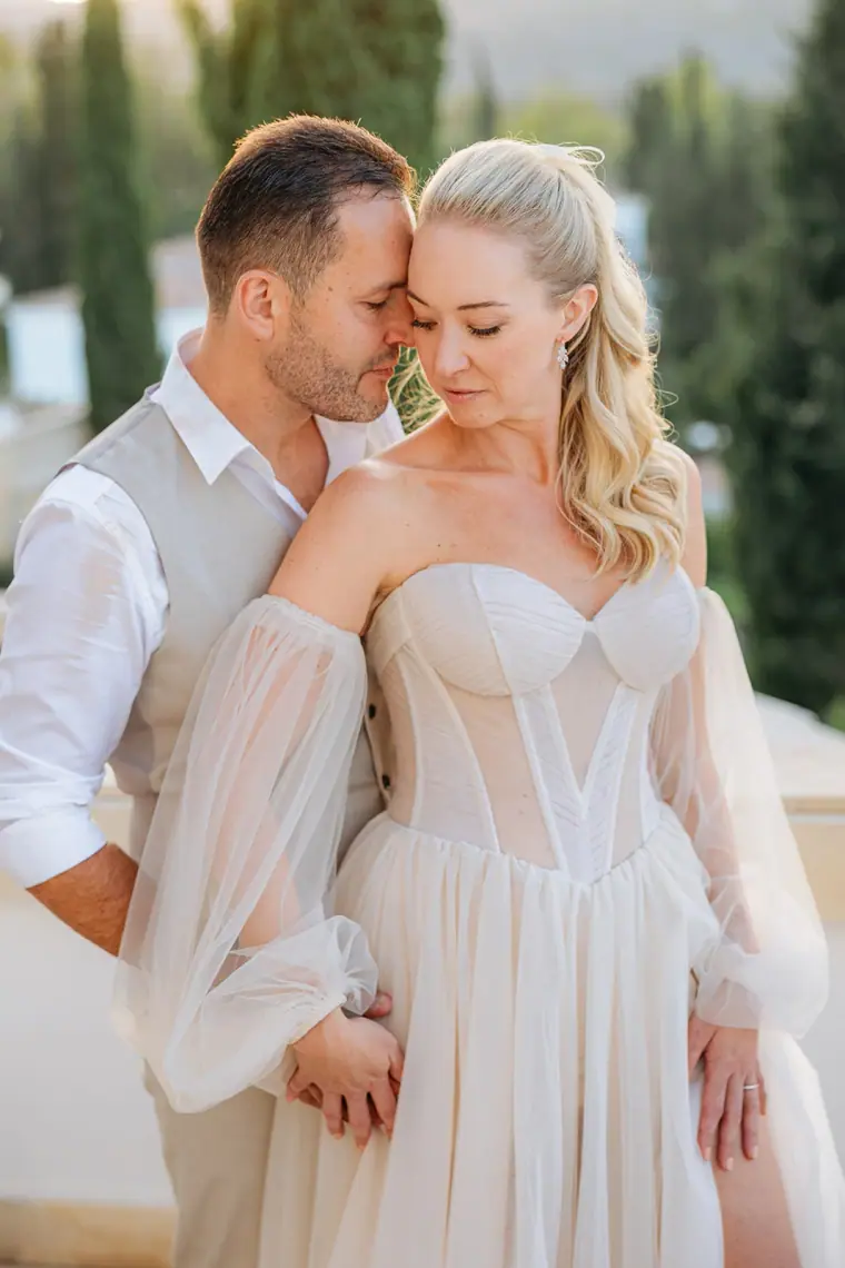 Jade and Peter cheek to cheek on the terrace among cypress trees
