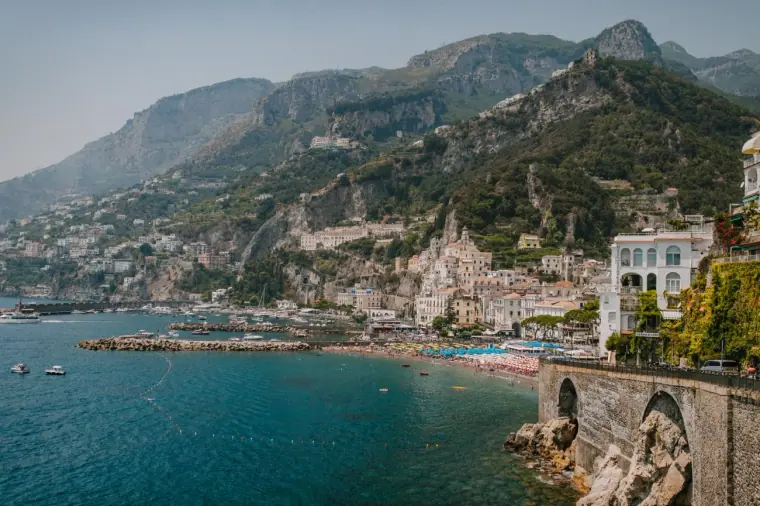 Pastel houses of Amalfi climbing the mountainside above turquoise water, Italy
