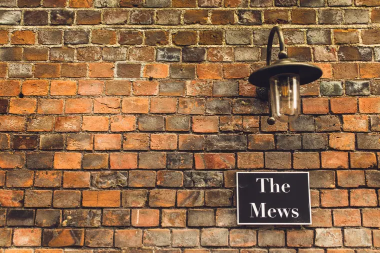 Brick wall with a lantern and a sign reading The Mews at Wasing Park