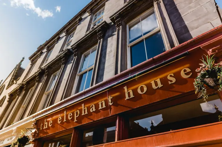 Red shopfront sign of The Elephant House café on an Edinburgh street, seen from below