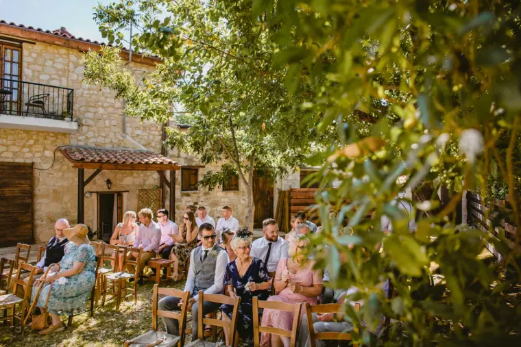 Guests seated for the ceremony in the stone courtyard at Vasilias Nikoklis Inn