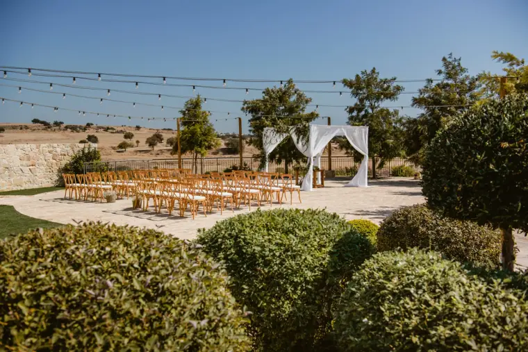 Ceremony chairs and white draped arch set on the terrace overlooking the countryside at Liopetro, Kouklia