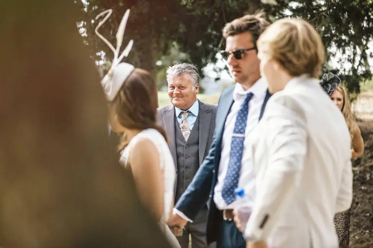 Guests in hats and suits mingling in the courtyard before the ceremony