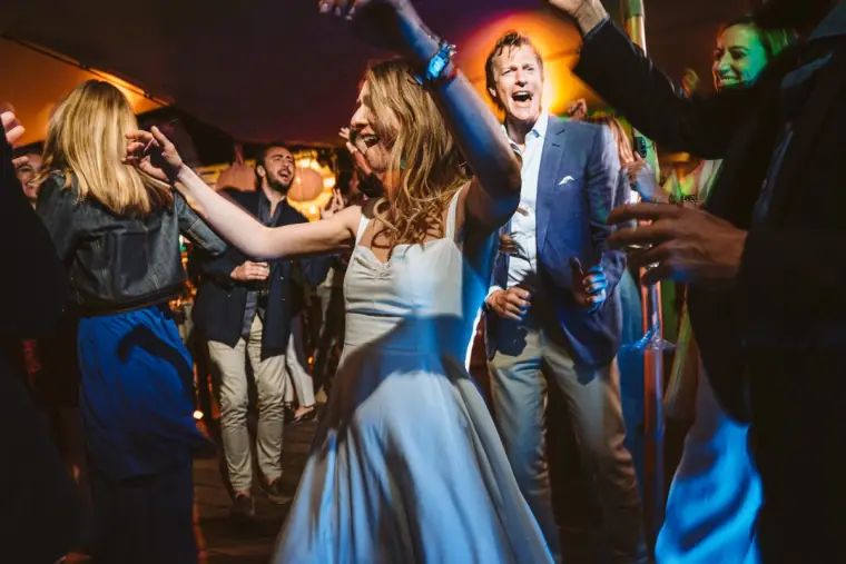 Bride dancing and singing with guests under coloured lights at the Ibiza party