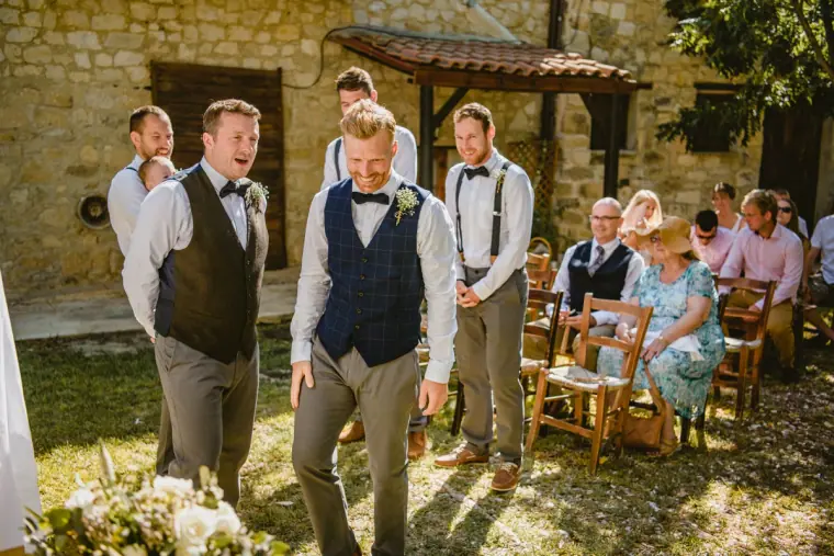 Groom laughing with his groomsmen as he waits at the front of the courtyard
