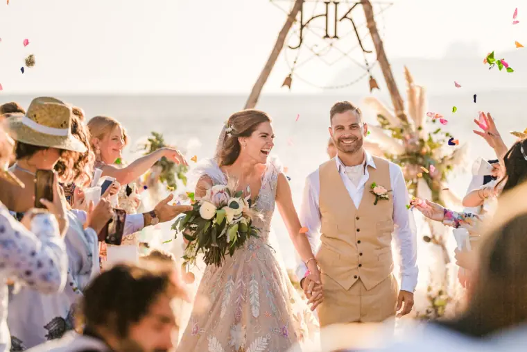 Kenton and Hassiba laughing as guests throw petals after the ceremony