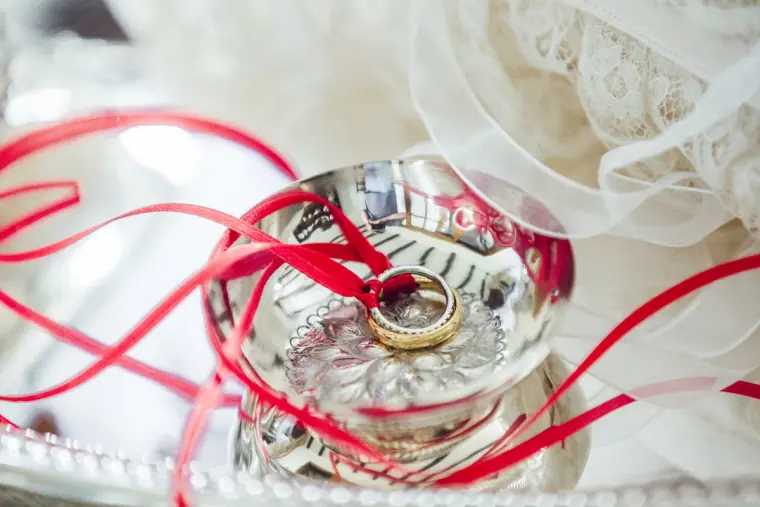 Wedding rings in a silver bowl tied with red ribbon