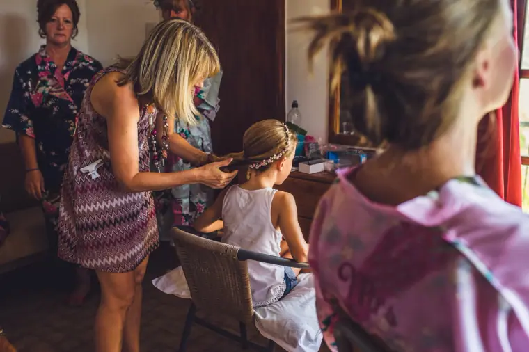 Bridal party getting ready, a young girl having her hair done in the bedroom