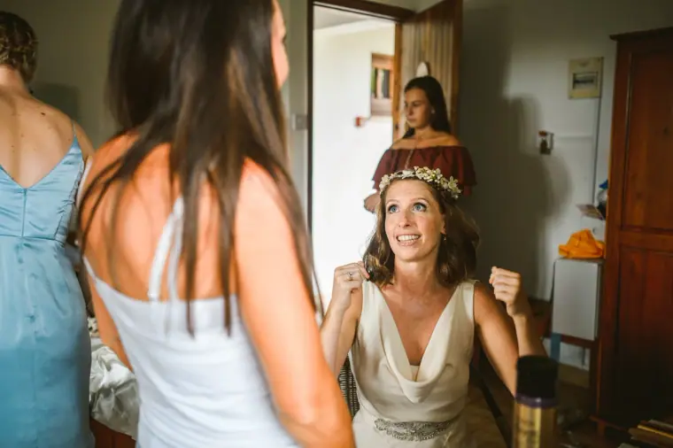 Bride in a flower crown smiling as bridesmaids gather around her