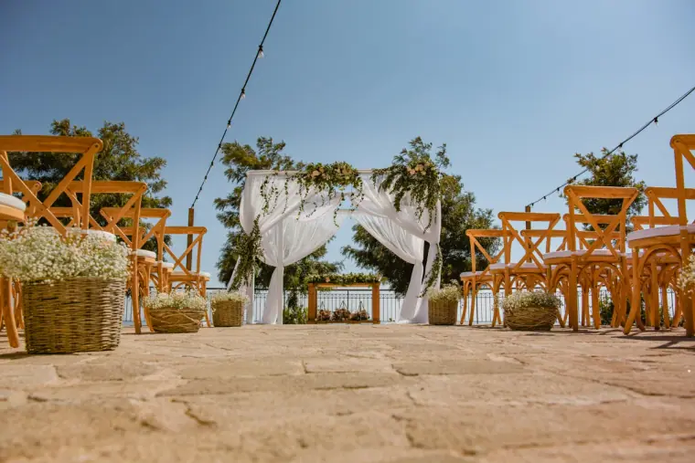 Wooden chairs, baskets of gypsophila and the draped arch on the ceremony terrace
