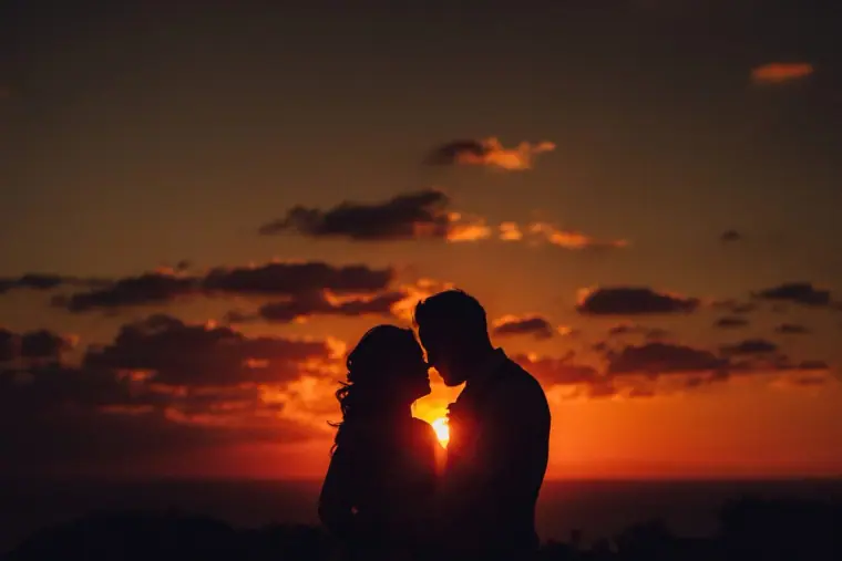 Bride and groom in silhouette, foreheads together, against a glowing red Ibiza sunset