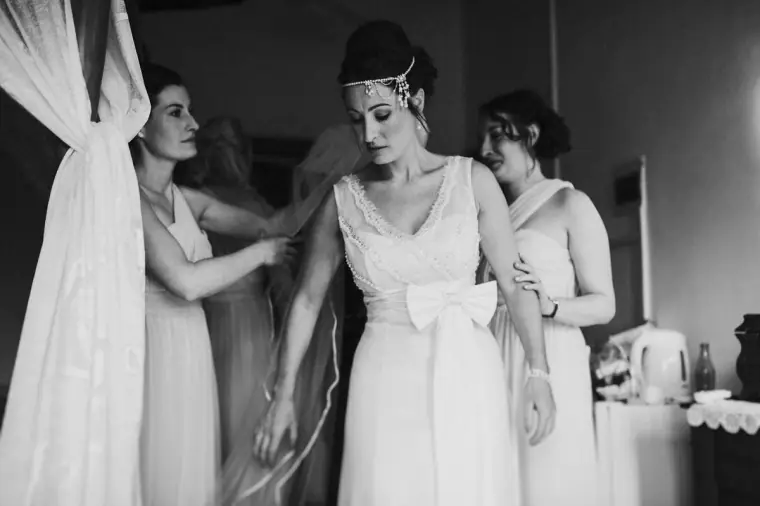 Black-and-white photo of bridesmaids helping Donna into her gown