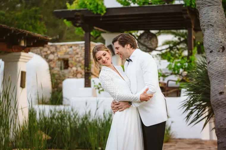 Antonia and Birger embracing by a whitewashed wall and pergola at Atzaro, Ibiza