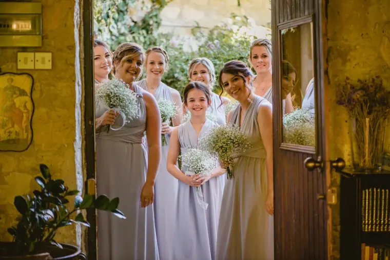 Bridesmaids in lilac grey peering out of a doorway with gypsophila bouquets