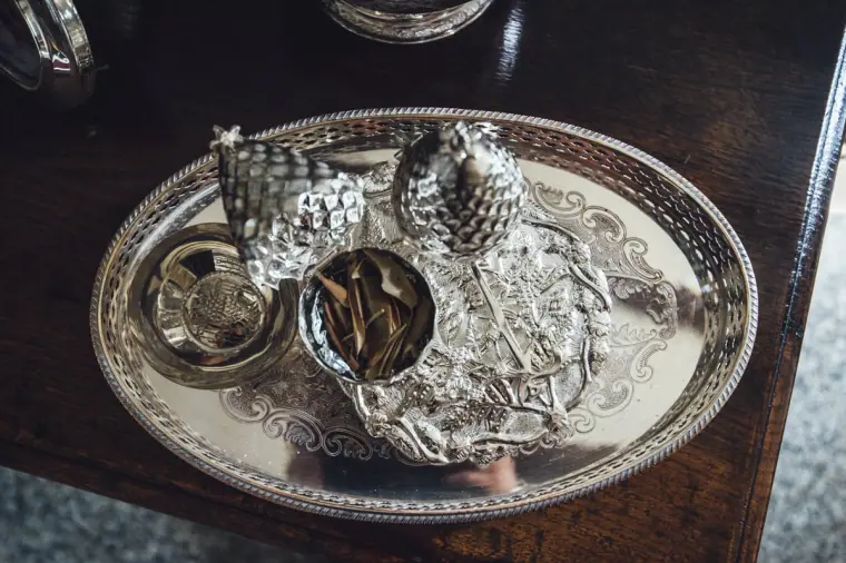 Silver tray holding a traditional incense burner and dried leaves