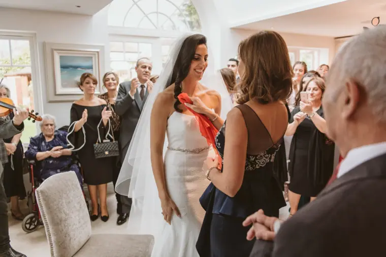 Bride greeting family in a bright room as violinists play