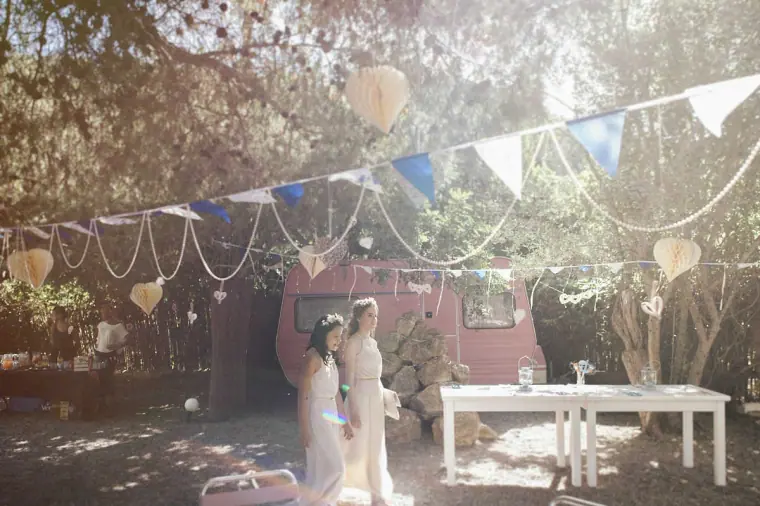 Bride arriving beneath pastel bunting in the shaded garden