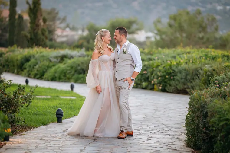 Jade and Peter standing together on a stone garden path at Anassa Hotel