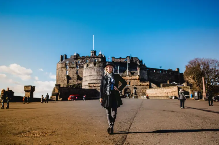 Woman walking across the esplanade towards Edinburgh Castle on a sunny day