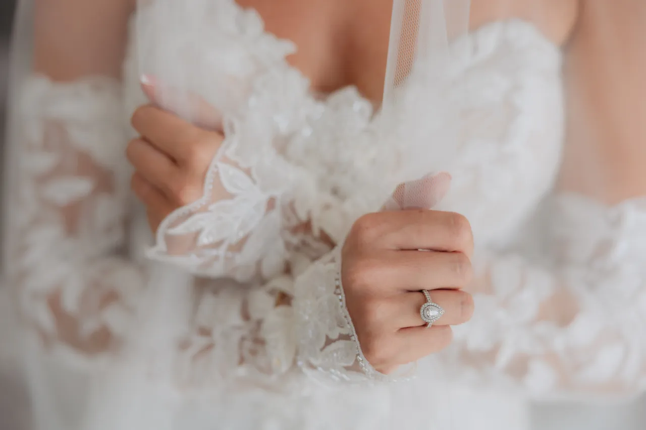 Close-up of the bride's lace sleeves and engagement ring
