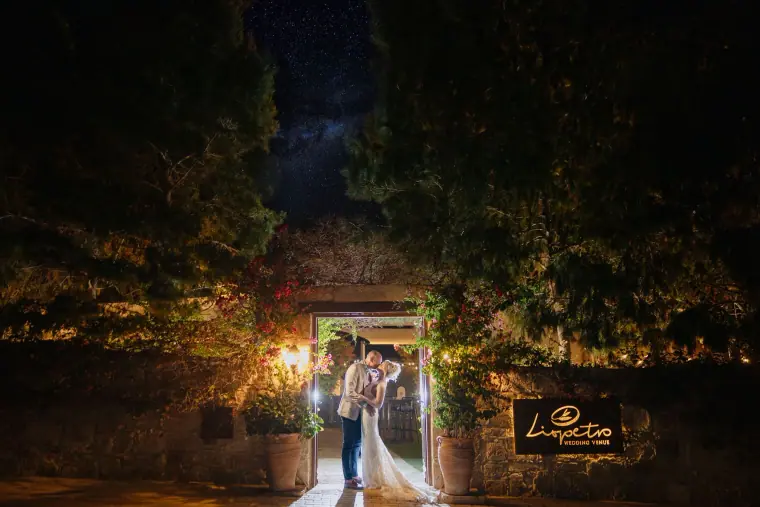 Couple in a lit gateway at night beneath a starry sky at Liopetro
