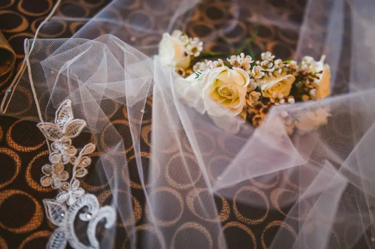 Ivory floral hair piece and an embellished veil laid on a patterned carpet