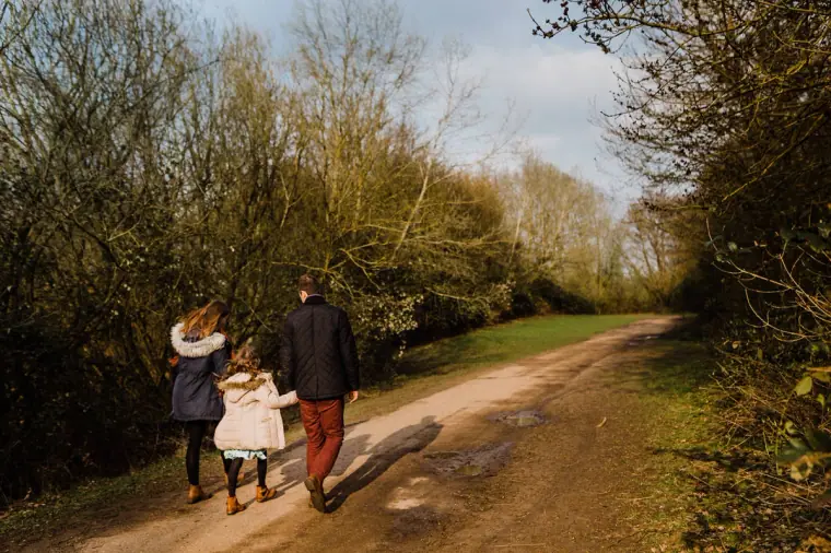 Couple walking hand in hand with a young girl along a country track