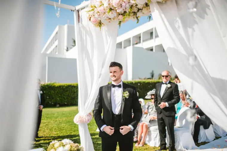 Steven waiting beneath the white draped ceremony canopy before the bride arrives