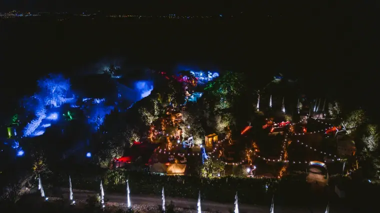 Garden party lit with blue and coloured lights seen from above at night