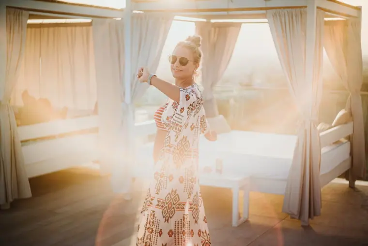 Woman dancing joyfully at golden hour among the rooftop daybeds at Napa Suites