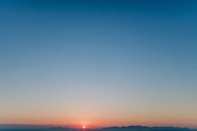 Gradient dusk sky as the sun dips below the horizon over the sea