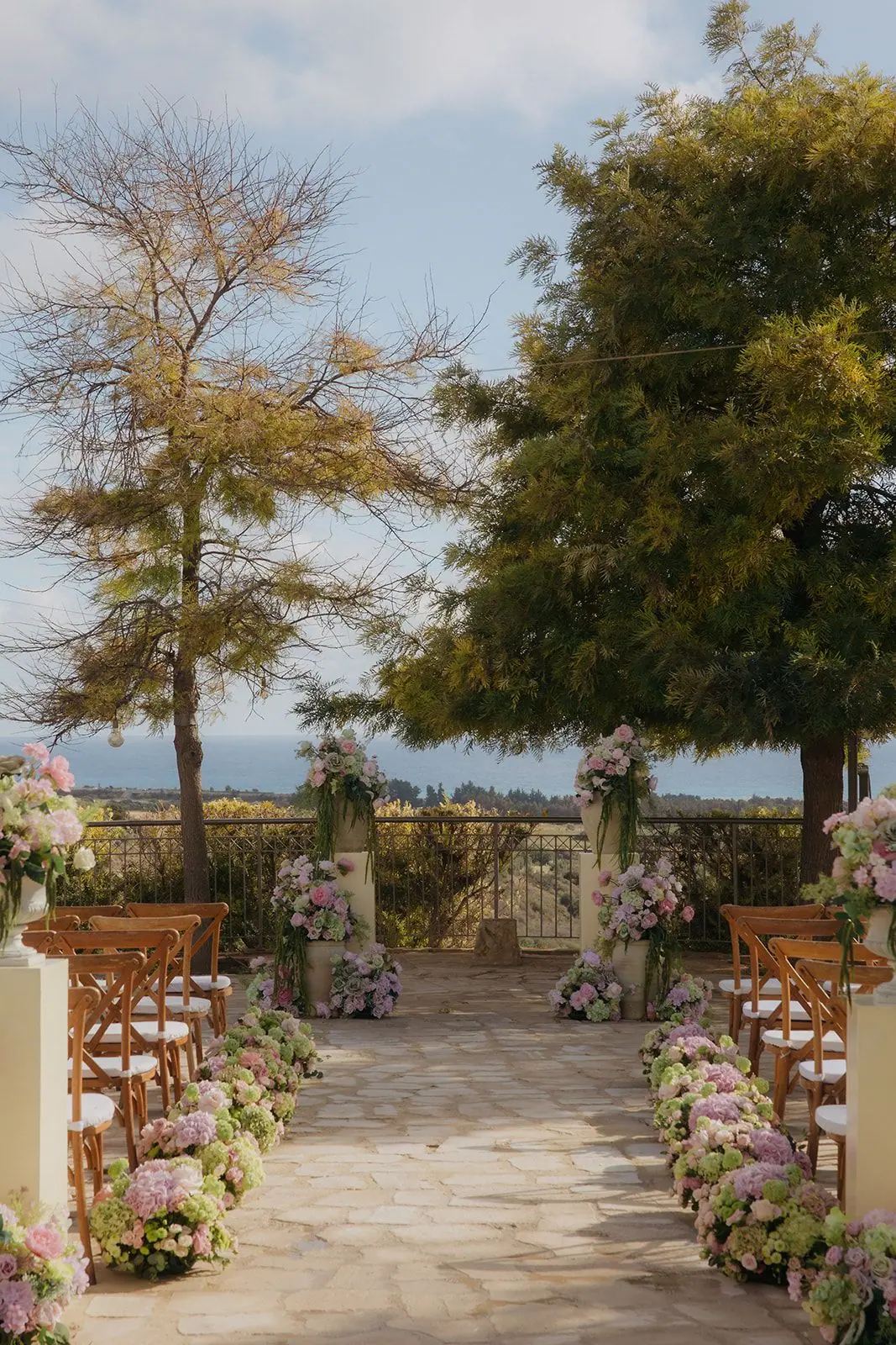 Aisle lined with hydrangeas between cream plinths at Liopetro