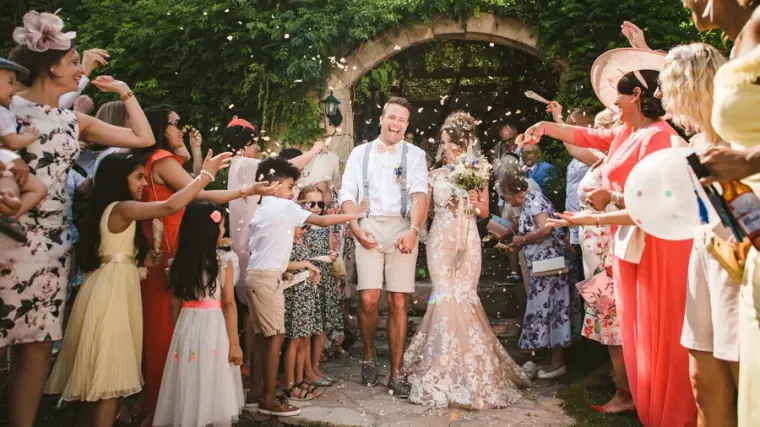 Confetti exit through a crowd of guests in front of the stone archway