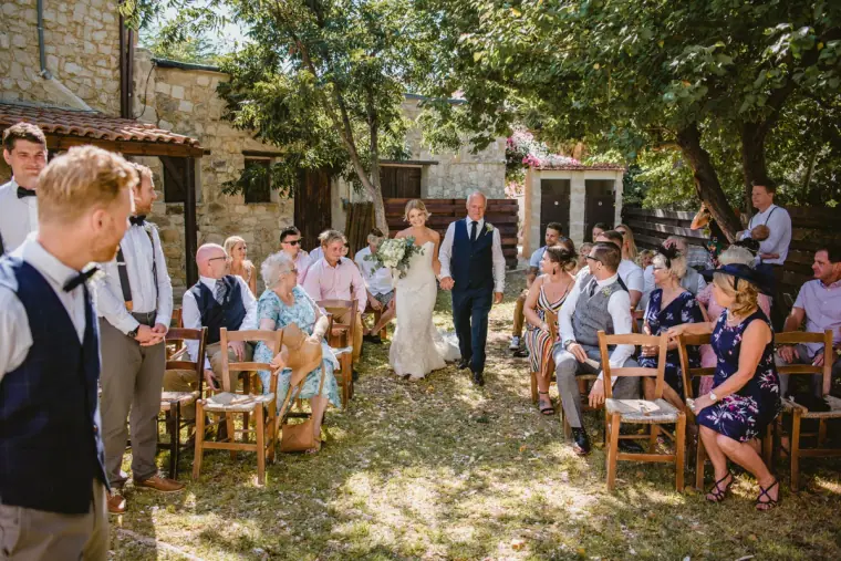 Bride walking down the aisle with her father as the groom waits