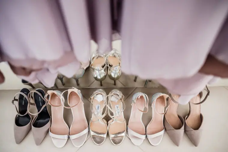 Bridesmaids' and bride's shoes lined up beneath lilac dresses