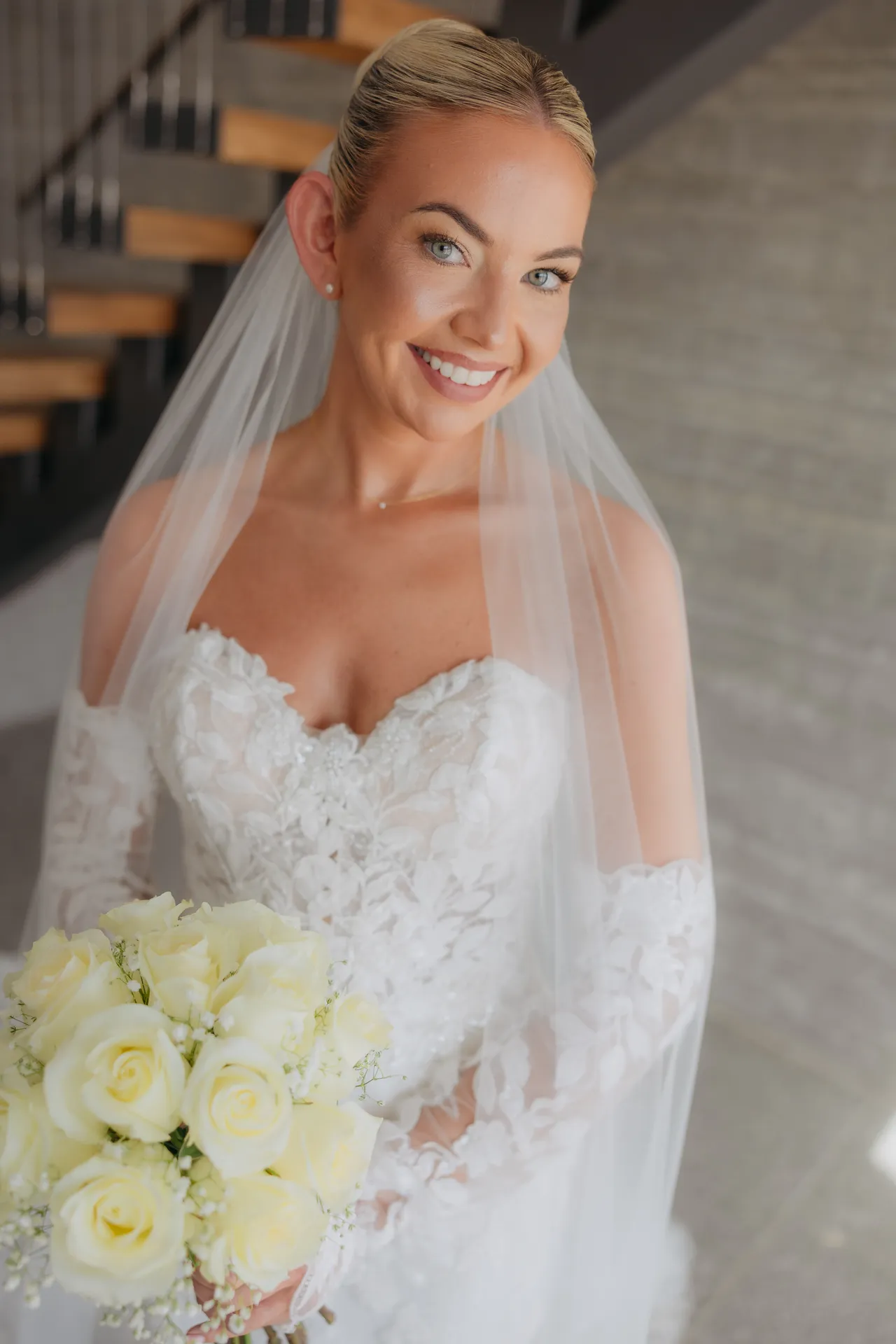 Olivia smiling in her veil, holding a bouquet of white roses