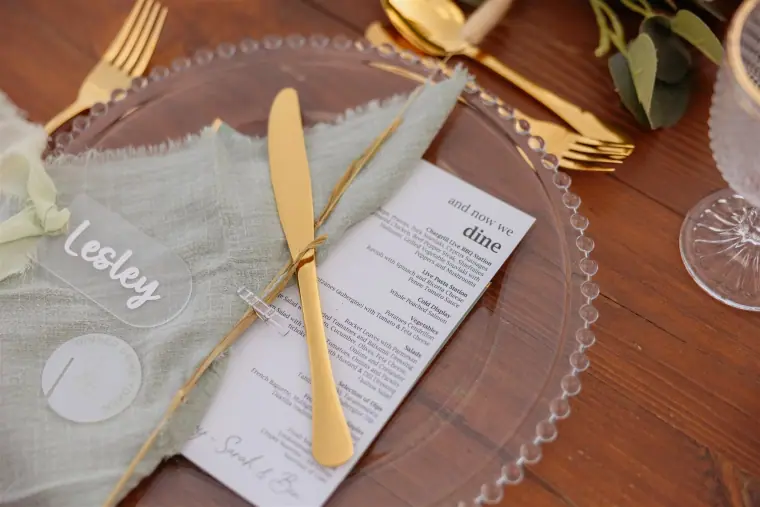 Place setting with a sage napkin, handwritten name, menu and gold cutlery