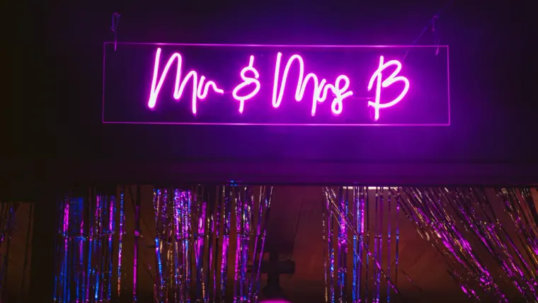 Purple neon sign reading Mr & Mrs B above a sparkling tinsel backdrop