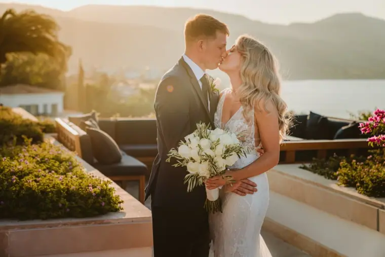 Carly and Jack kissing at golden hour on a sea-view terrace, Anassa Hotel