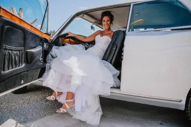 Louise stepping out of a vintage white car in her full-skirted gown