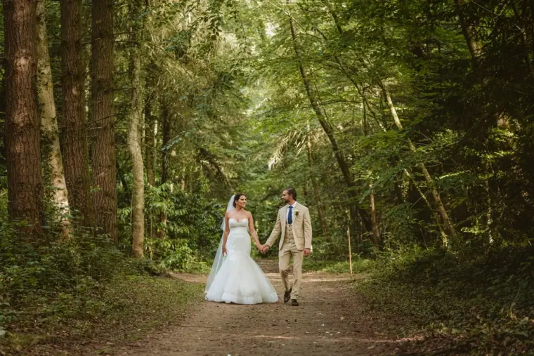 Lauren and Josh walking hand in hand along a forest track