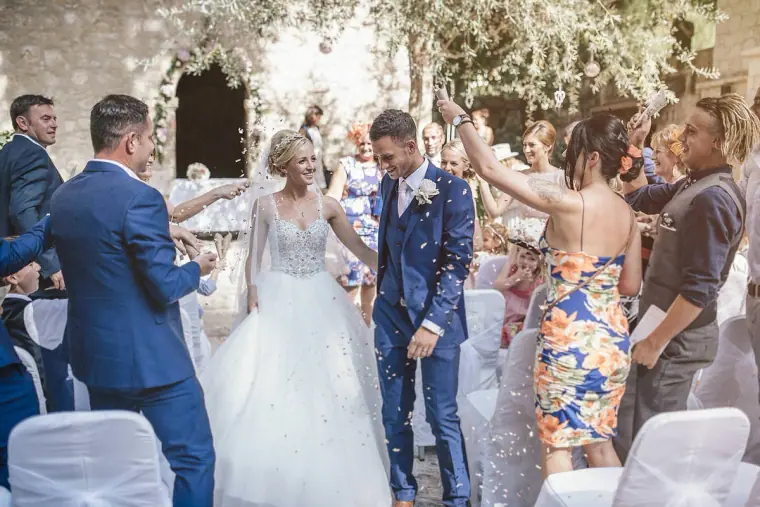 Guests showering Emmee and Danny with petals as they walk back down the aisle