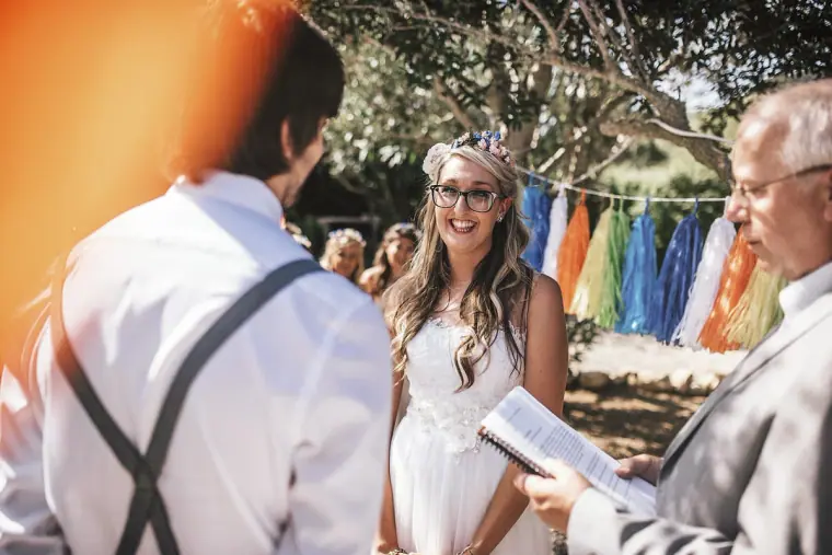 Bride smiling at the groom as the celebrant reads from a book