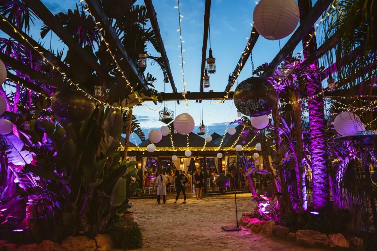 Purple-lit garden under a pergola of fairy lights and lanterns at night, Atzaro