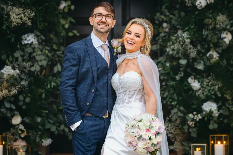 Ian and Jade smiling together in front of white flowering foliage