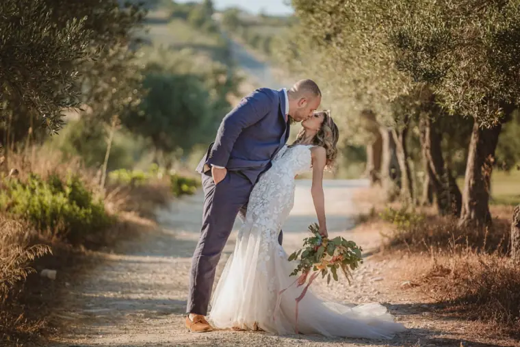Chris dipping Emily for a kiss on a gravel path through the trees
