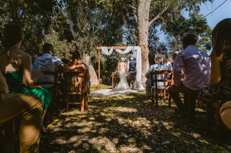 Couple at the white-draped arch, seen from the back of the seated guests